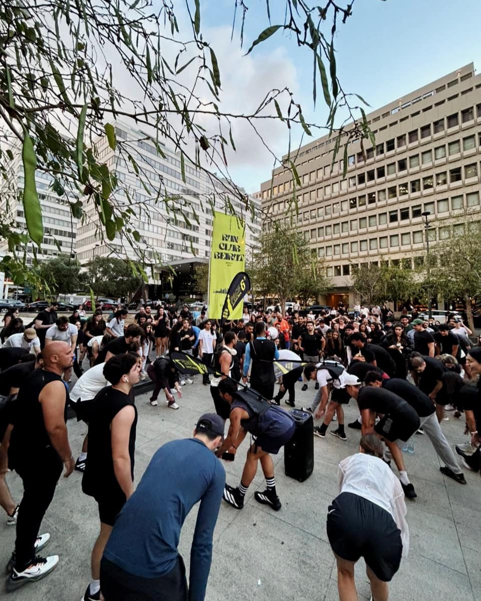 Run Club Beirut members warming up together under the club flags before a run