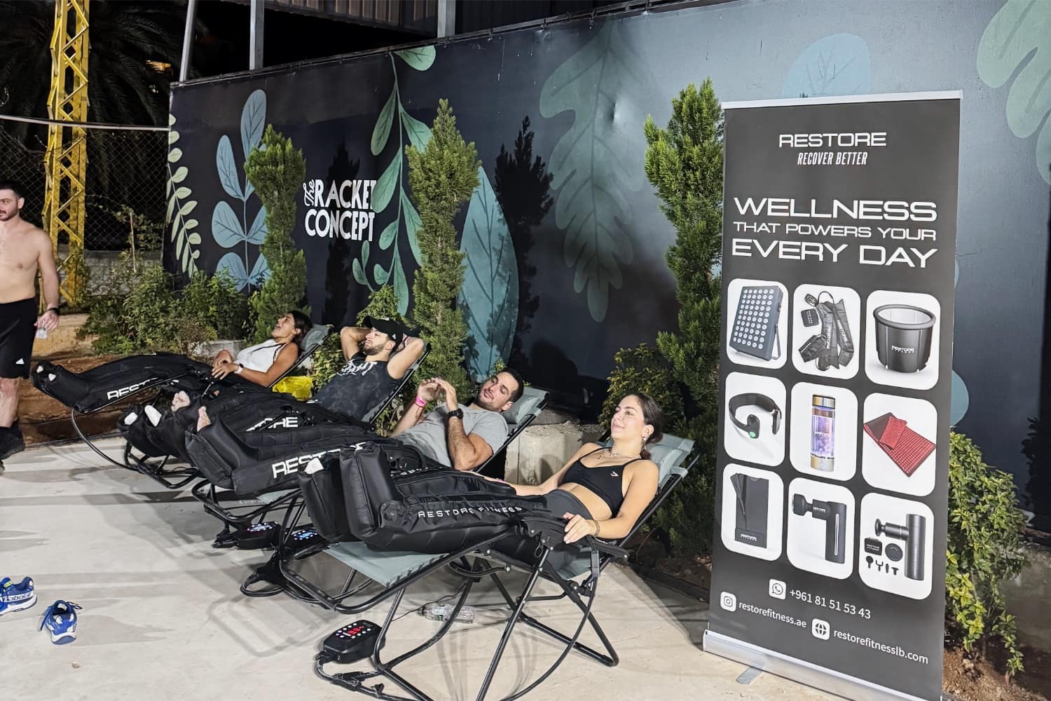 Members reclining in compression boots on loungers at the recovery area after dark