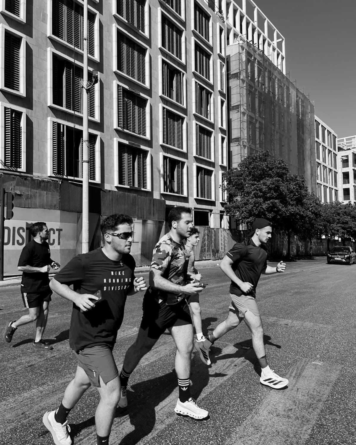 Three Run Club Beirut runners mid-stride on a Downtown Beirut street between concrete buildings