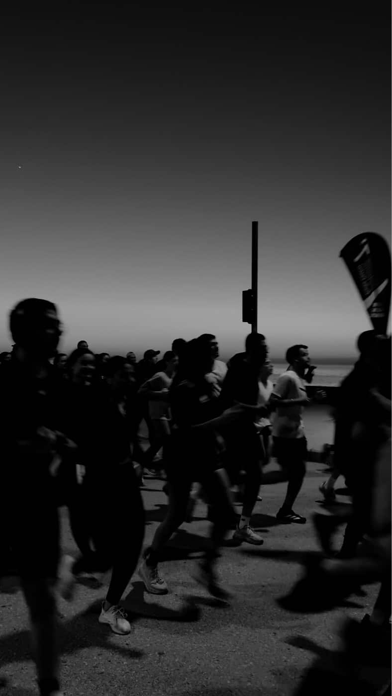 Run Club Beirut runners crossing the Beirut seafront at dusk, the sea and the last of the light behind them